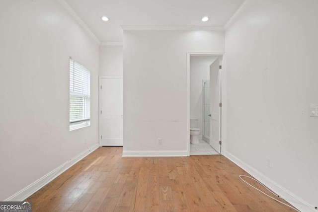 unfurnished bedroom featuring light wood-type flooring, ensuite bathroom, and crown molding