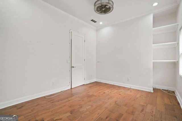 empty room with ornamental molding and wood-type flooring