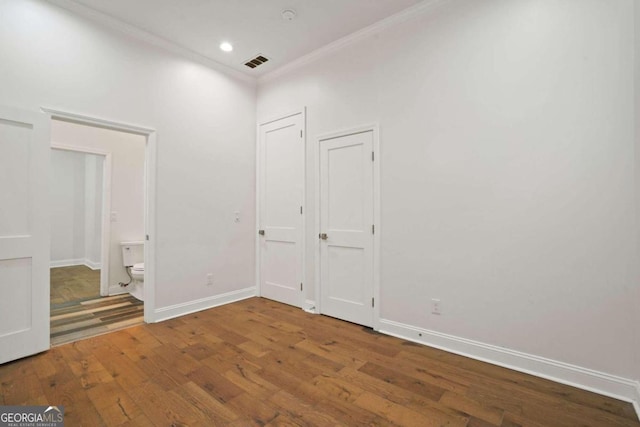 interior space with ornamental molding, connected bathroom, and hardwood / wood-style floors