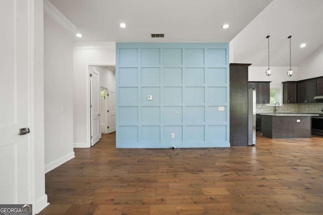 unfurnished living room featuring ornamental molding, lofted ceiling, dark wood-type flooring, and sink