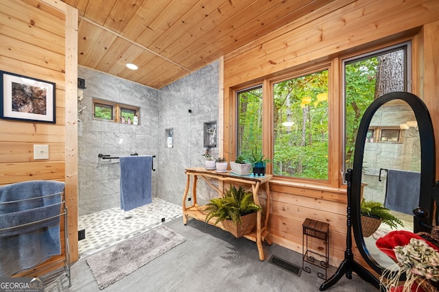 bathroom featuring concrete floors, wood walls, and walk in shower