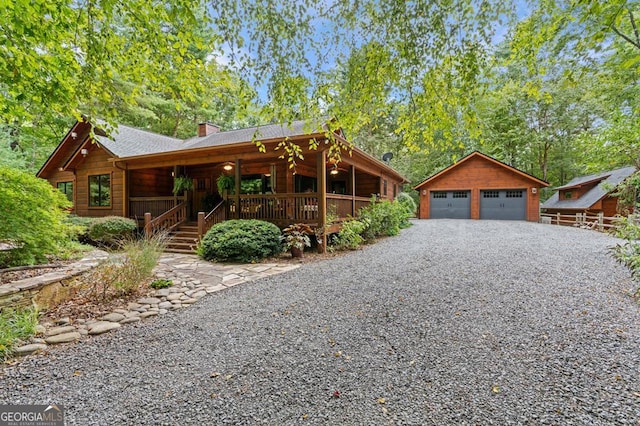 cabin with covered porch, an outbuilding, and a garage