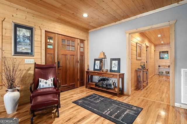 living area with wood ceiling, wooden walls, and hardwood / wood-style floors