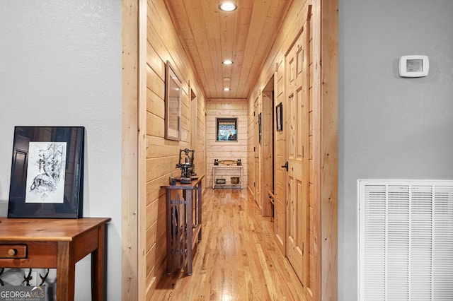 corridor with wood ceiling, wood walls, and light hardwood / wood-style floors