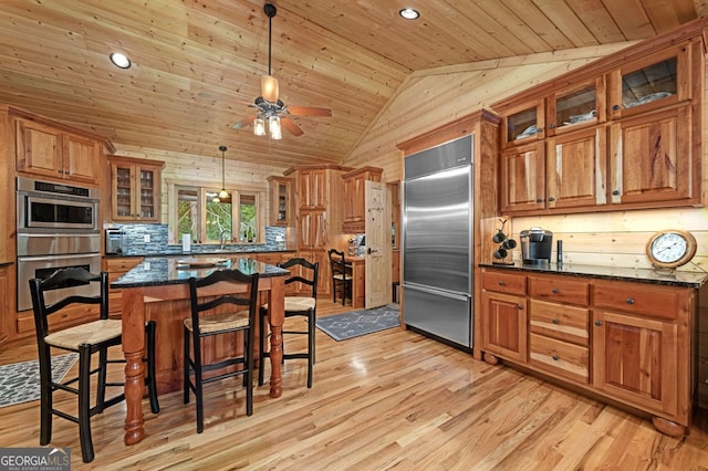 kitchen with pendant lighting, vaulted ceiling, stainless steel appliances, dark stone countertops, and wooden ceiling