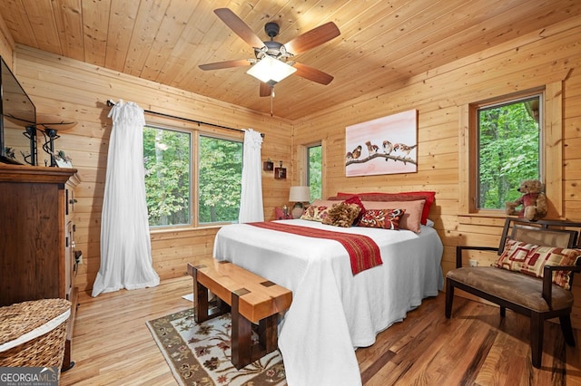 bedroom featuring light hardwood / wood-style flooring, wood walls, and ceiling fan