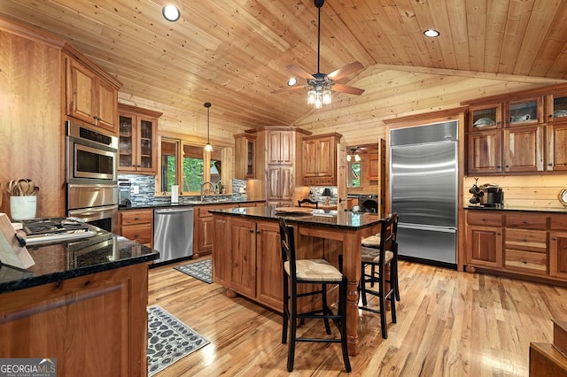 kitchen featuring hanging light fixtures, stainless steel appliances, a center island, ceiling fan, and light hardwood / wood-style flooring