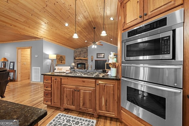 kitchen with ceiling fan, decorative light fixtures, light hardwood / wood-style flooring, a fireplace, and vaulted ceiling