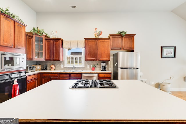 kitchen featuring sink, backsplash, stainless steel appliances, lofted ceiling, and hardwood / wood-style flooring