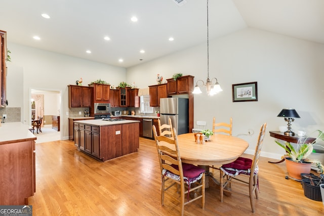 kitchen featuring a kitchen island, backsplash, light wood-type flooring, stainless steel appliances, and decorative light fixtures