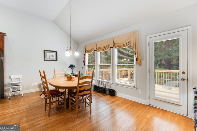 dining area with an inviting chandelier, lofted ceiling, and hardwood / wood-style floors