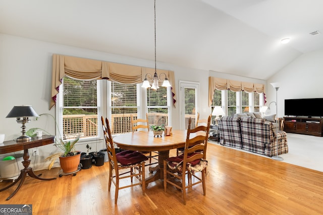 dining area with hardwood / wood-style floors, vaulted ceiling, and a notable chandelier