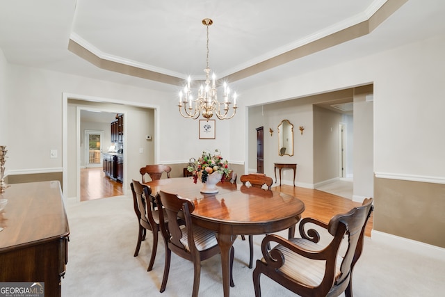 carpeted dining space featuring crown molding, a tray ceiling, and an inviting chandelier