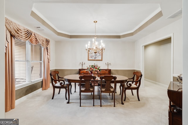 dining room featuring ornamental molding, light carpet, a tray ceiling, and an inviting chandelier