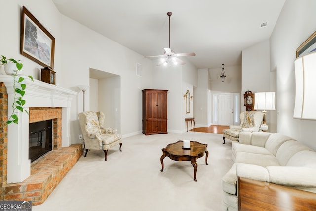 carpeted living room with a high ceiling, a brick fireplace, and ceiling fan