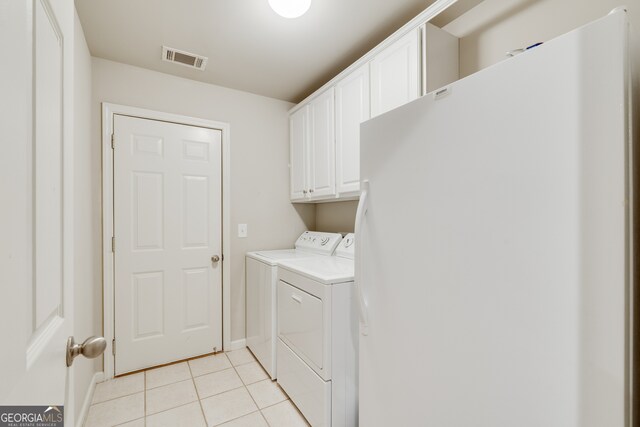 clothes washing area with washer and dryer, light tile patterned floors, and cabinets