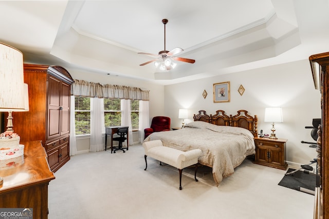 bedroom featuring light carpet, ornamental molding, ceiling fan, and a raised ceiling