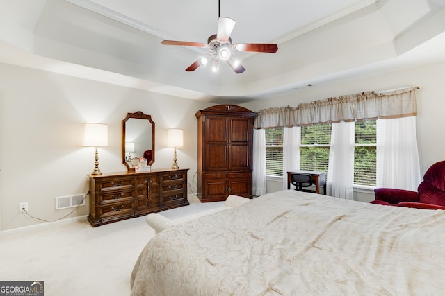 carpeted bedroom featuring crown molding, ceiling fan, and a raised ceiling