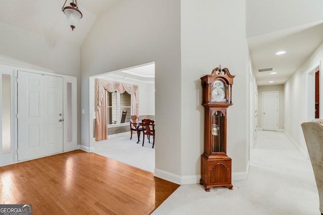 foyer with hardwood / wood-style floors and high vaulted ceiling