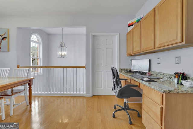 office area with built in desk, light wood-type flooring, and an inviting chandelier