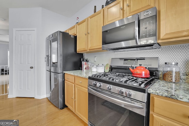 kitchen featuring light hardwood / wood-style flooring, stainless steel appliances, light stone counters, and decorative backsplash