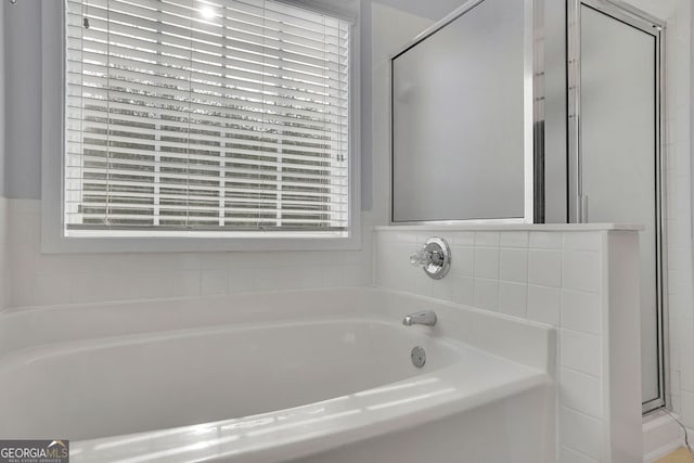 bathroom with shower with separate bathtub and plenty of natural light