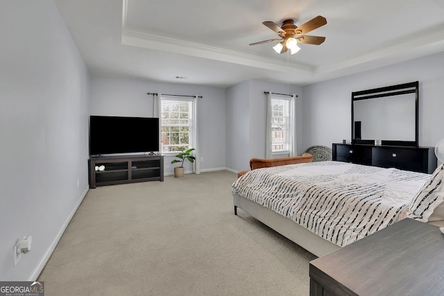 bedroom with light carpet, a tray ceiling, and ceiling fan