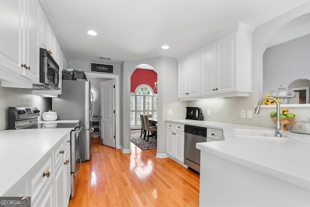 kitchen featuring light hardwood / wood-style floors, tasteful backsplash, sink, stainless steel appliances, and white cabinets