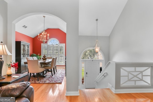 entrance foyer with an inviting chandelier, hardwood / wood-style floors, and high vaulted ceiling