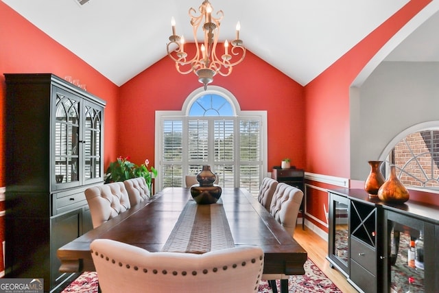 dining area featuring wine cooler, light wood-type flooring, a chandelier, and vaulted ceiling