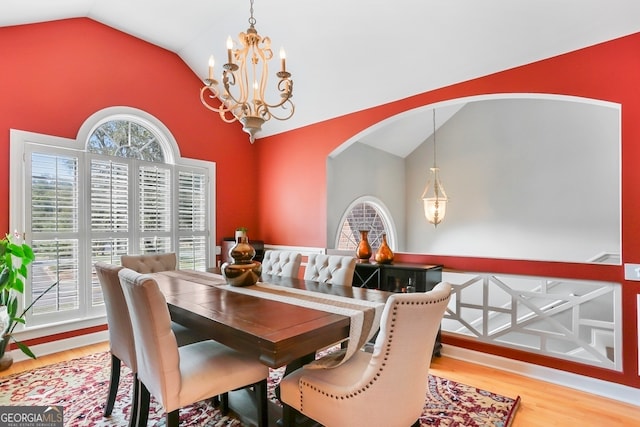 dining area featuring hardwood / wood-style floors, a chandelier, and vaulted ceiling