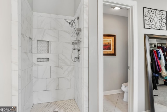 bathroom featuring a tile shower, tile patterned floors, and toilet