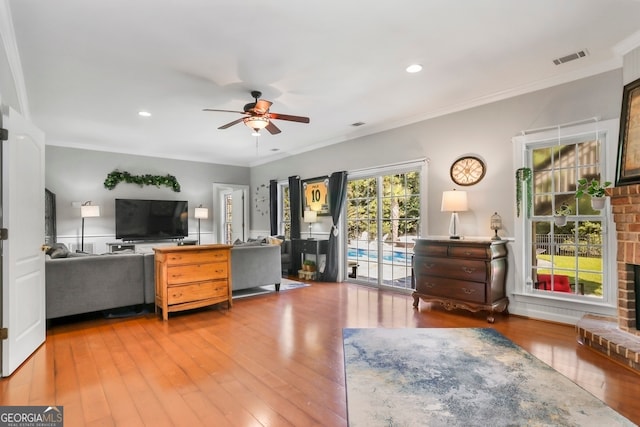 interior space featuring ceiling fan, ornamental molding, hardwood / wood-style floors, a fireplace, and access to exterior