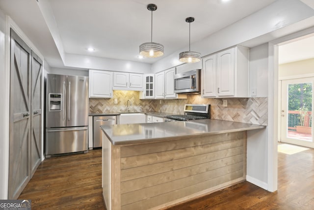 kitchen featuring appliances with stainless steel finishes, kitchen peninsula, white cabinets, and dark hardwood / wood-style flooring