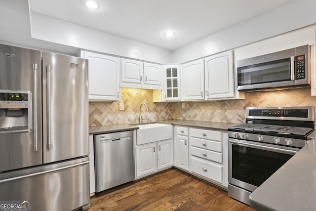 kitchen with appliances with stainless steel finishes, white cabinetry, tasteful backsplash, and dark hardwood / wood-style flooring