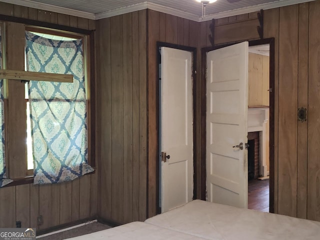 unfurnished bedroom with wood walls and ornamental molding