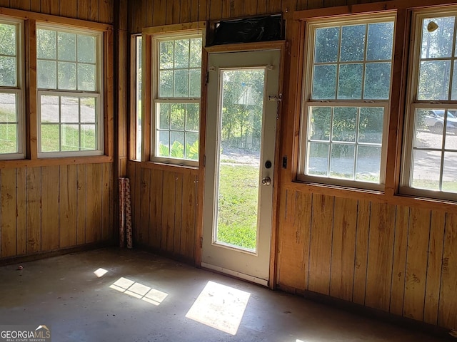 doorway to outside featuring wooden walls and plenty of natural light