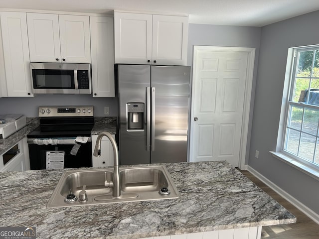 kitchen featuring appliances with stainless steel finishes, stone countertops, white cabinetry, and sink