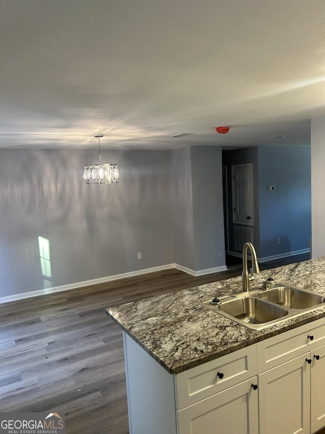 kitchen featuring dark hardwood / wood-style floors, white cabinets, dark stone countertops, sink, and decorative light fixtures