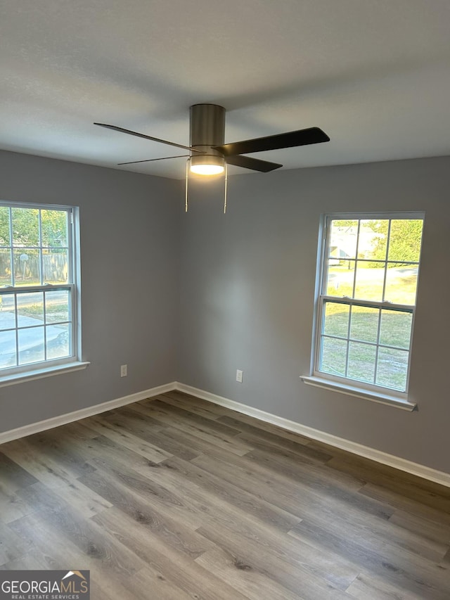 empty room with ceiling fan, a wealth of natural light, and hardwood / wood-style floors