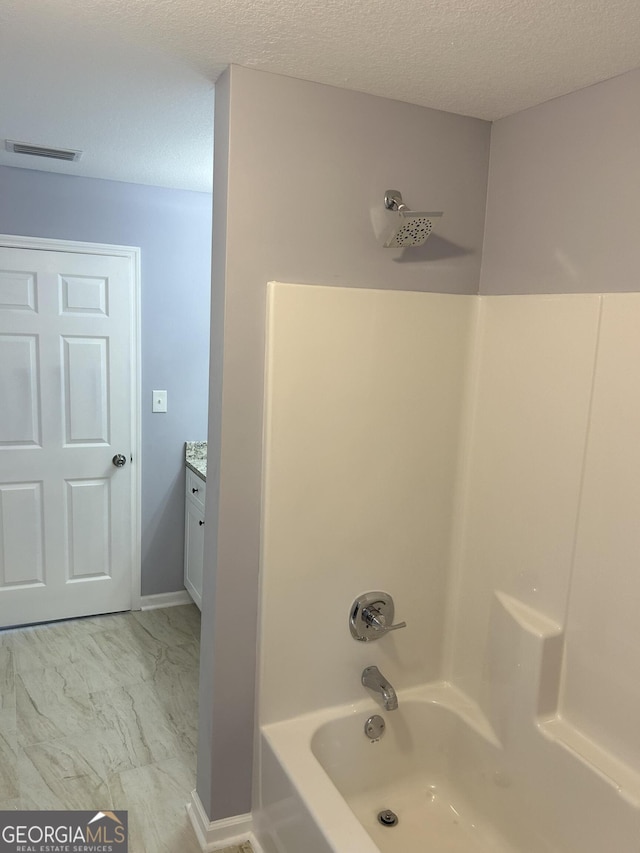 bathroom featuring shower / bath combination, vanity, and a textured ceiling