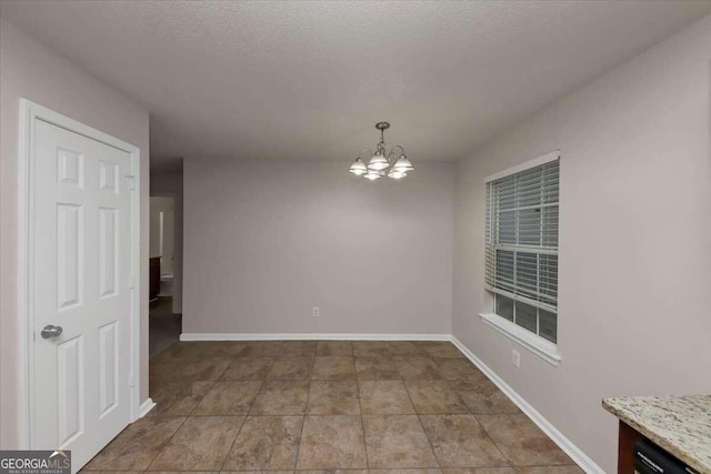 empty room with a textured ceiling and an inviting chandelier