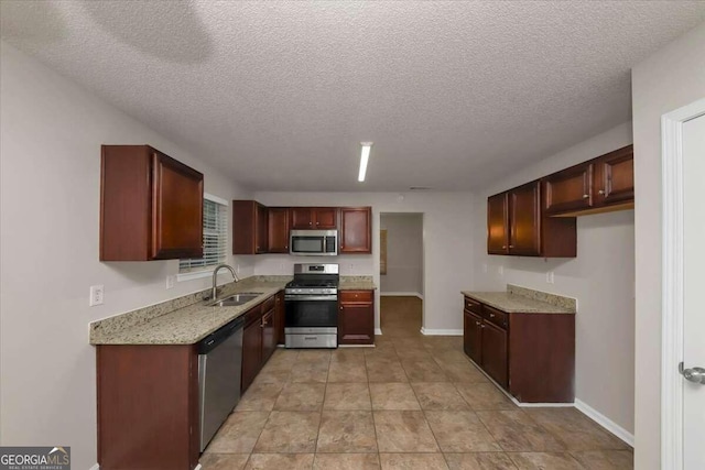 kitchen with light stone countertops, stainless steel appliances, a textured ceiling, and sink