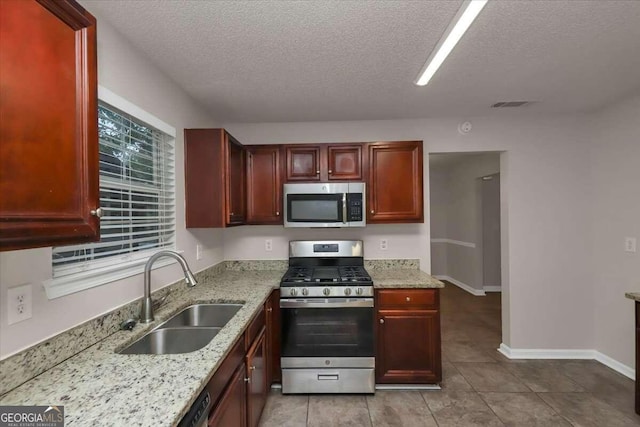 kitchen with a textured ceiling, sink, stainless steel appliances, and light stone counters