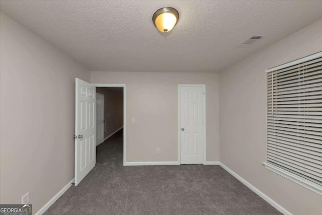 unfurnished bedroom featuring dark colored carpet and a textured ceiling