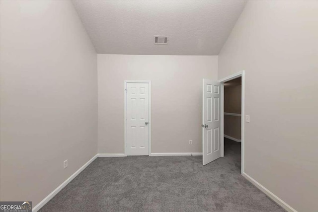 unfurnished bedroom with carpet floors, a textured ceiling, and vaulted ceiling