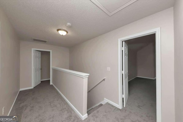 corridor with a textured ceiling and light colored carpet