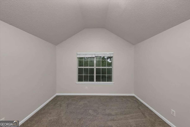 carpeted empty room featuring a textured ceiling and lofted ceiling