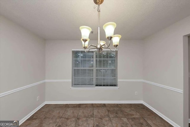 unfurnished dining area featuring a textured ceiling and an inviting chandelier