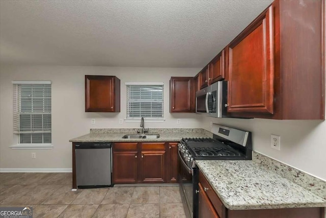 kitchen with light stone countertops, stainless steel appliances, a textured ceiling, and sink